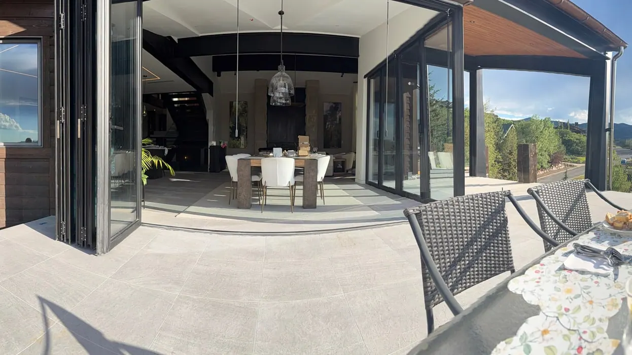 Long-span opening at a covered patio — A folding glass wall spanning the full width of the opening — the header over it is doing considerably more work than the finish suggests